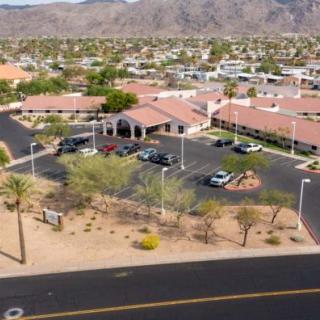 Aerial view of a building surrounded by a desert landscape with mountains in the background and a parking lot in front.