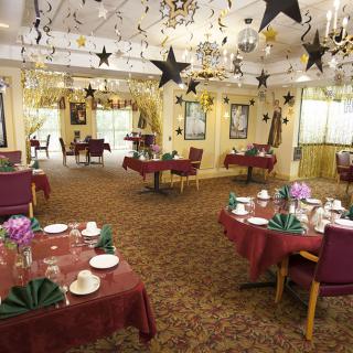 A festively decorated dining room with tables set and chandeliers hanging from the ceiling.