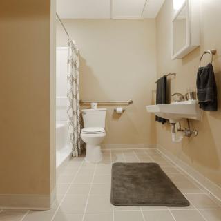 A clean and modern bathroom with neutral colors, featuring a sink, toilet, and shower.
