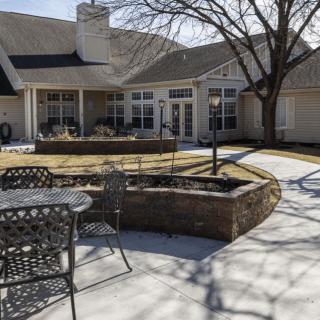 A sunny residential backyard with a patio and seating area.