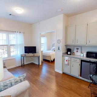 A cozy apartment with a living area and kitchenette, featuring a television and large windows.