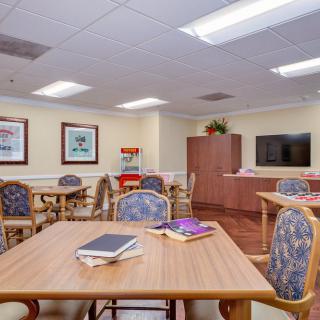 A well-lit room with multiple tables, chairs, artwork on the walls, and a television.