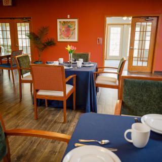 A cozy dining area with neatly set tables and warm orange walls.