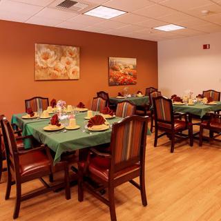 A cozy dining room with neatly arranged tables and chairs, adorned with place settings and wall art.