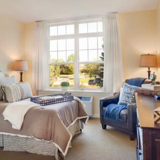 A cozy bedroom with a large window, comfortable bed, and elegant decor.