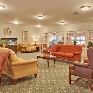 A cozy living room area featuring several sofas, armchairs, and a central wooden coffee table on a patterned carpet.