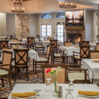 A beautifully arranged dining area featuring elegant tables and chairs, with chandeliers hanging overhead.