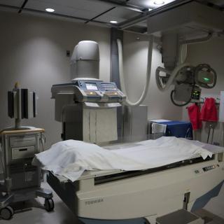 A hospital examination room featuring an X-ray machine and a bed.