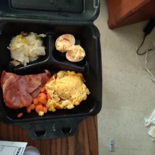 A packed meal featuring eggs, ham, carrots, and vegetables.