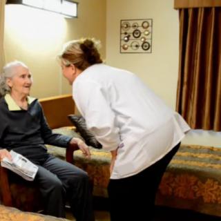 A caregiver attending to an elderly woman in an assisted living facility.