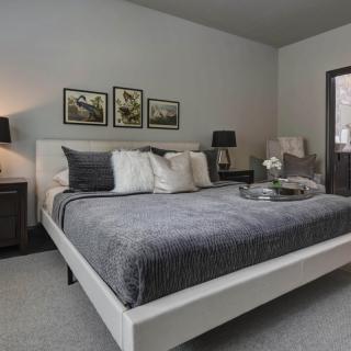 A modern and elegant bedroom with neutral tones, featuring a comfortable double bed, stylish lamps on bedside tables, and framed artwork above the headboard.