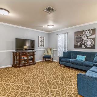 A cozy living room featuring a patterned carpet, blue couch, television, and stylish artwork on the wall.