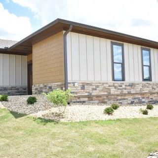 A modern house exterior with stone siding and landscaped yard.