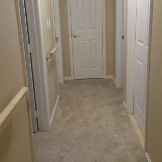A carpeted hallway with multiple doors leading to different rooms.
