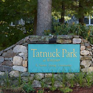 The entrance sign for Tatnuck Park, set against a stone wall with greenery.
