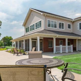 A modern two-story house with a spacious patio and well-maintained lawn under a clear sky.