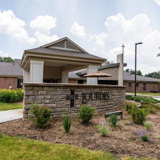 The entrance to a building complex featuring a landscaped area and signage.
