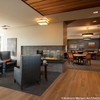 A modern interior with a cozy sitting area featuring a fireplace, complemented by a dining space in the background.