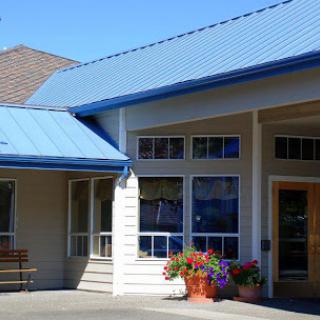 A welcoming building featuring a blue roof and colorful flower pots at the entrance.