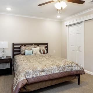 A cozy bedroom with a comfortable bed, nightstand, and ceiling fan.