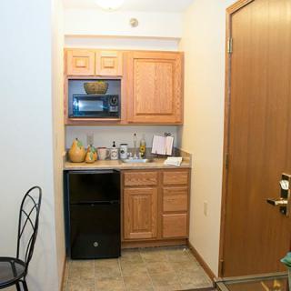 A small kitchenette with a microwave, mini fridge, and wooden cabinets.