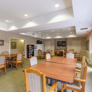 A spacious dining area with multiple tables and chairs arranged neatly under bright ceiling lights.