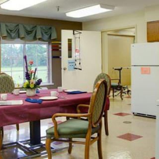 A cozy dining area with a table set for meals, surrounded by chairs, and a refrigerator in the background.
