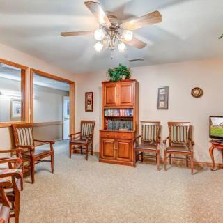 A cozy waiting room with wooden chairs and a bookshelf under a ceiling fan.
