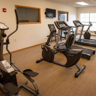 A small gym featuring various cardio machines, including treadmills, an elliptical, and a stationary bike.