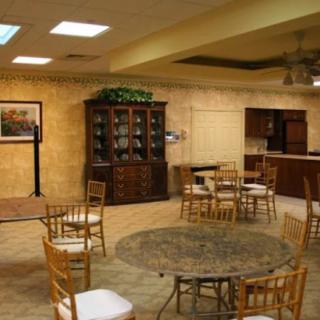 A well-furnished indoor space with multiple tables and chairs, a large cabinet, and soft lighting.