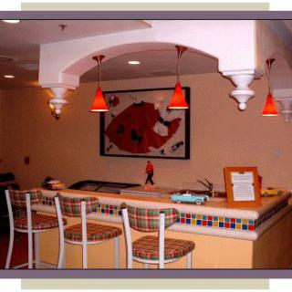 A cozy bar with high stools, warm lighting, and colorful decor.