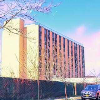 A modern building contrasted against a vibrant sky and bare trees.