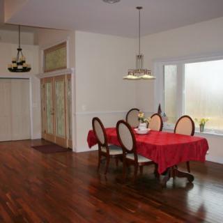 A cozy dining room with a red tablecloth and wooden flooring.