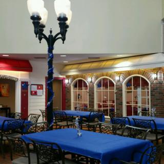 An indoor restaurant setting with blue tablecloths and a central lamppost.