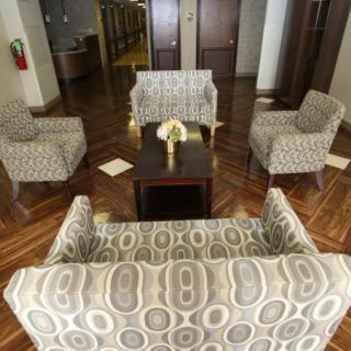 A cozy seating area in a lobby with patterned chairs and a sofa surrounding a coffee table.