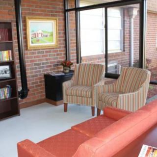 A cozy living room with brick walls, featuring comfortable seating and a large window.