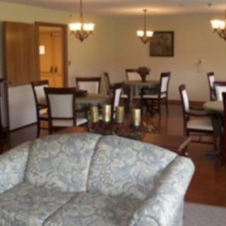 A dining and living area with elegant chandeliers, a sofa, and wooden flooring.