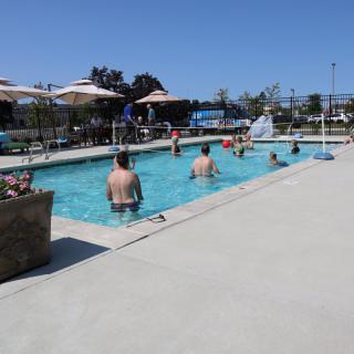 People enjoying a sunny day at the outdoor swimming pool.