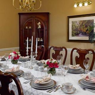 A formal dining room with a beautifully set table, featuring candlesticks and floral centerpieces.