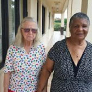 Two elderly women walking together, holding hands.