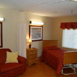 A cozy room with a bed, sofa, and warm lighting.