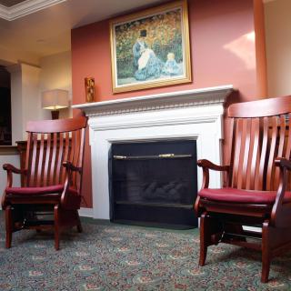 A cozy living room with two wooden rocking chairs flanking a fireplace, adorned with framed artwork above.