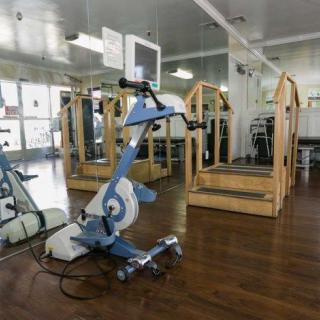 An exercise bike in a gym with wooden flooring and mirrored walls.