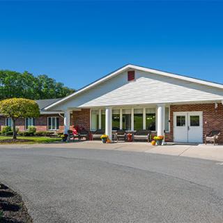 A building with a large entrance surrounded by a driveway and landscaped area under a clear blue sky.