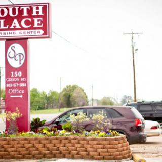 A parking area with vehicles next to a business sign for South Place Nursing Center.