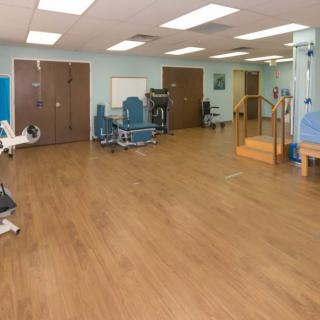 A spacious rehabilitation clinic equipped with exercise machines and therapy tools.