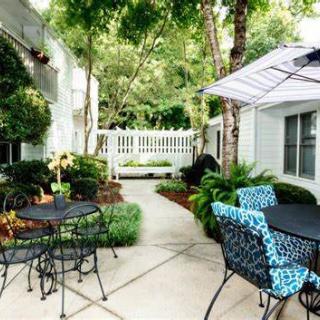 A cozy outdoor patio area with tables, chairs, and lush greenery.