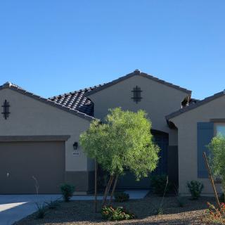 A modern suburban single-story house with a garage and landscaped front yard under a clear blue sky.