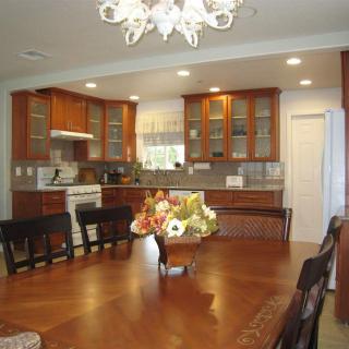 A cozy kitchen and dining area with wooden cabinets, a large table, and a decorative chandelier.