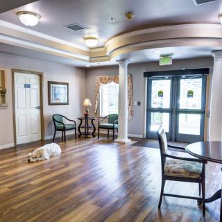 A spacious lobby area with wooden flooring, seating arrangements, and decorative lighting.